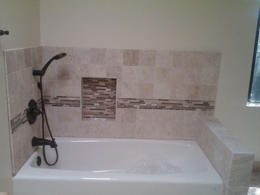 Tile bathtub surround with mosaic accent band and recessed niche.