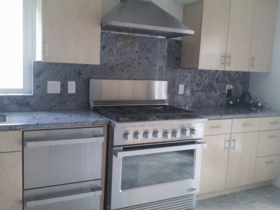 Kitchen with light wood-grain cabinets, stainless gas range, and granite counters.