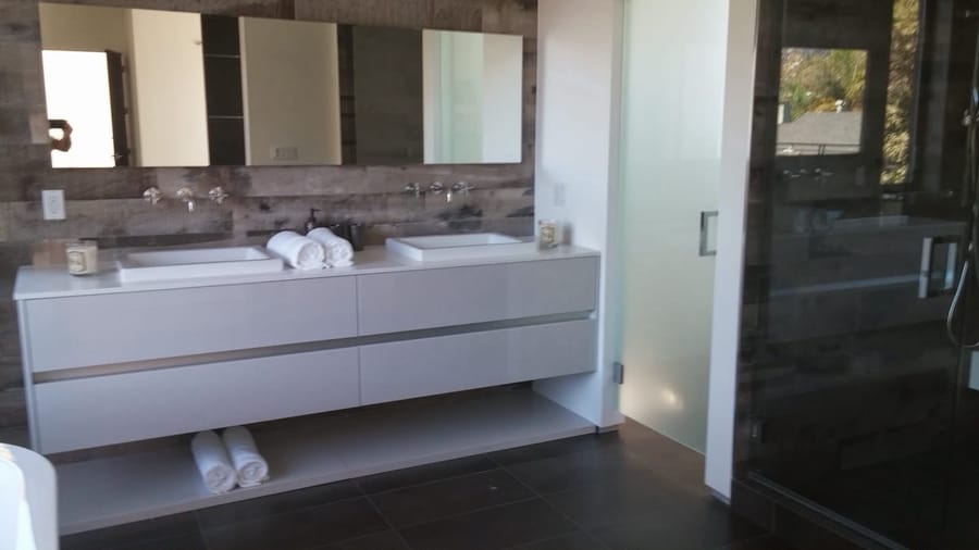 Modern primary bathroom with floating double vanity, vessel sinks, and frosted glass shower.
