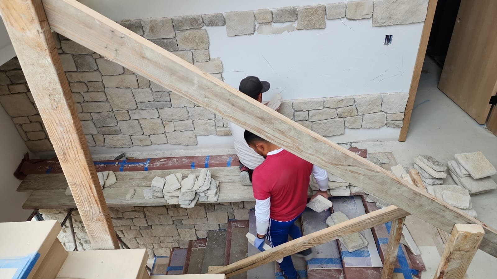 Exterior wall finish in progress on a VIP build — natural stone applied over a properly prepared envelope.