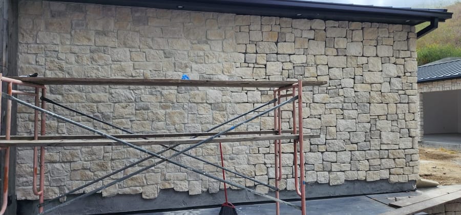 Exterior detail of a VIP-built home — natural stone veneer wall under a new roofline.