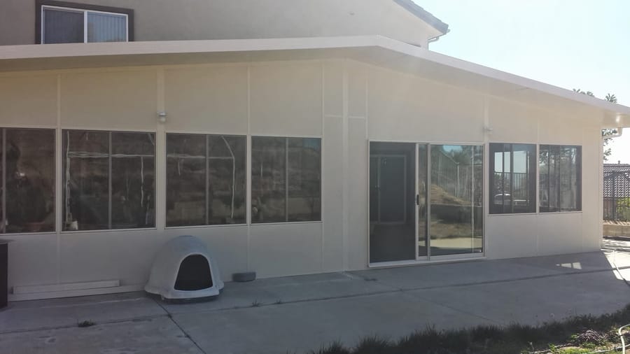 Glass-walled patio enclosure attached to the home with matching roofline.