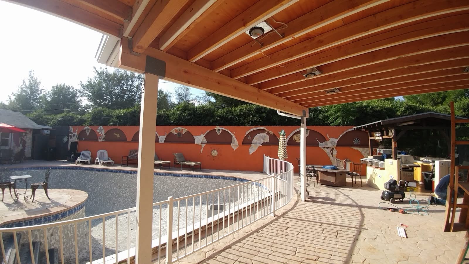 Custom wood pergola structure attached to the home, framing a poolside patio.